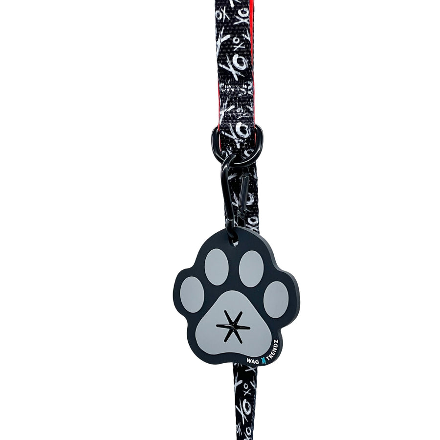 Poop Buddy - black and gray resin dog paw - hanging on a black & white XO dog leash with red accents - against white background - Wag Trendz