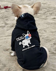 Dog wearing a black hoodie with Fart Like a Frenchie Rescue Like a Hero  on a sandy background